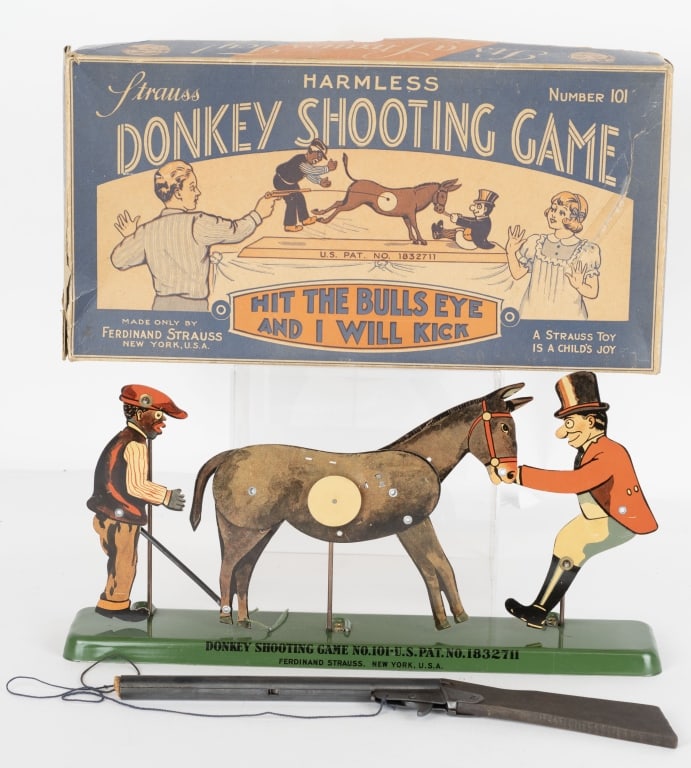 STRAUSS DONKEY TIN SHOOTING GAME w/ BOX: Strauss Donkey Shooting Game. New York: Ferdinand Strauss, ca. 1920s. A tin litho toy featuring an stable hand that gets kicked into the air by the donkey once the center target is hit. Includes origi