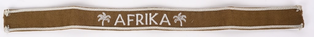 WWII NAZI GERMAN OFFICERS AFRIKA CUFFTITLE WW2: Woven, brushed, khaki/tan, camelhair construction cufftitle features machine embroidered, capitalized Latin script, "Afrika", flanked by palm trees to either side in silvery/gray rayon threads. The to