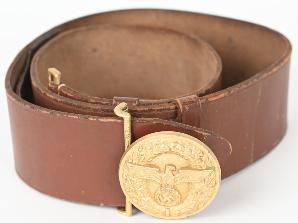 WWII NAZI NSDAP POLITICAL LEADER'S BELT & BUCKLE: A 57mm wide, 100cm long, Havana brown leather belt, with its cast, gilt-washed aluminum belt buckle. The roughly 56mm diameter buckle features, to its convex obverse, a spread-winged eagle clutching a