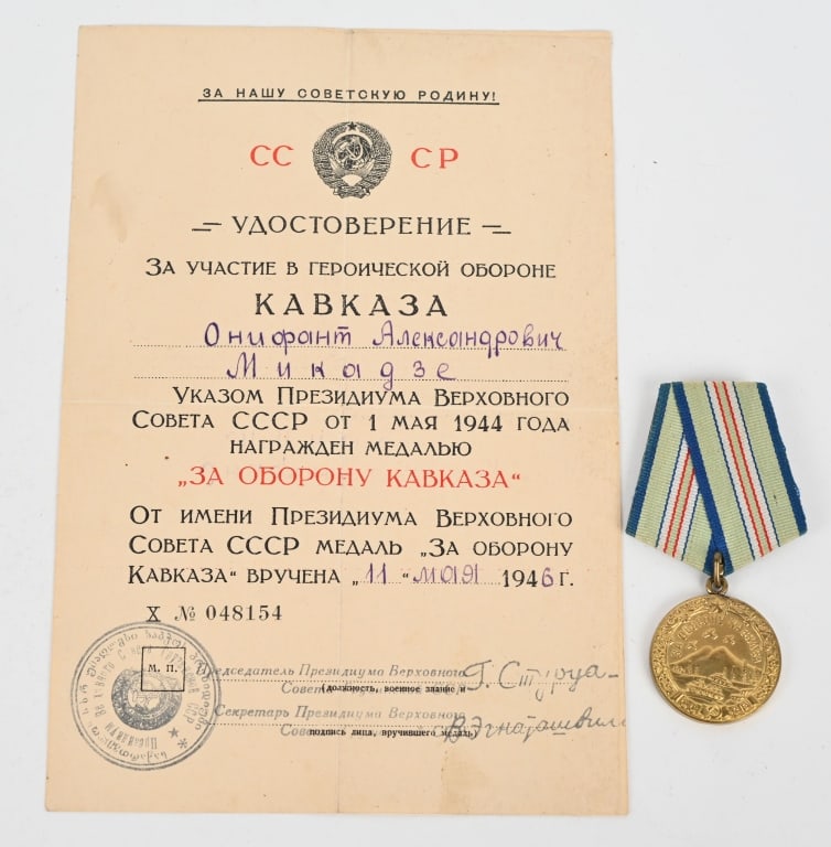 WWII SOVIET DEFENSE OF CAUCASUS MEDAL W DOCUMENT: Medal for the Defense of Caucasus, Variation 1, 1940s issue. In brass; measures 36.9 mm in height (incl. eyelet), 32.0 mm in width; weighs 17.4 g not including the suspension and connecting link. Vari