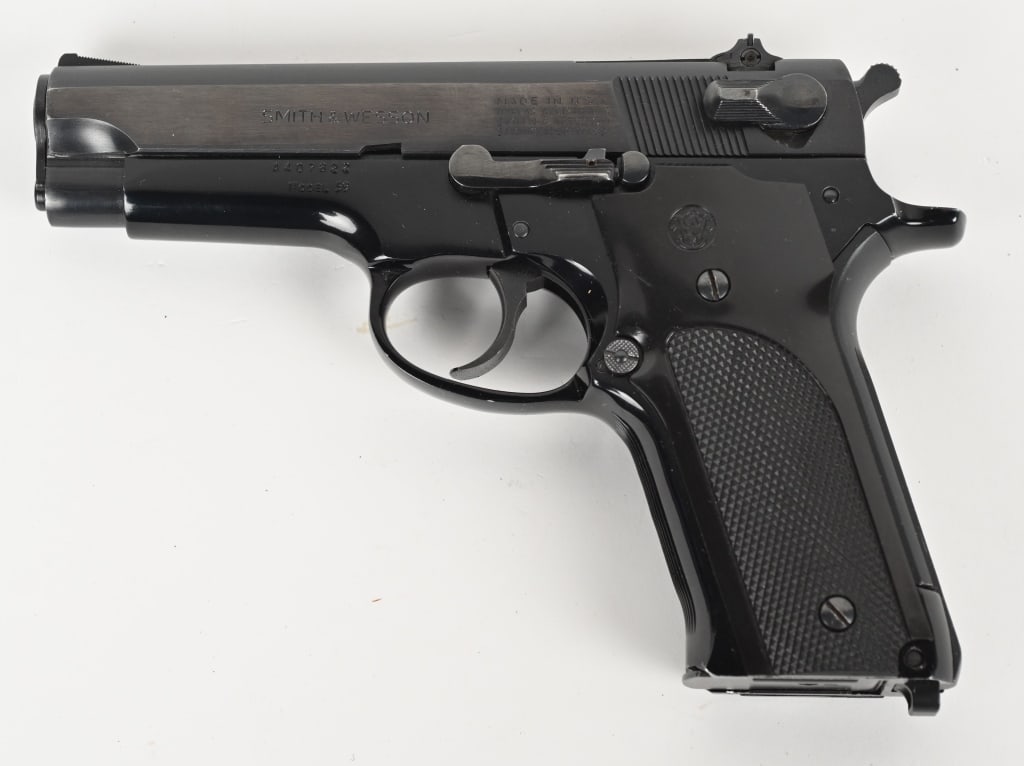 SMITH & WESSON MODEL 59 SEMI AUTOMATIC 9MM: SERIAL NUMBER: A407822. BARREL: 4 1/4". CALIBER: 9MM. MANUFACTURED: 1980s. Slide is blue steel with adjustable rear sight and ramped front. Alloy frame is black coated with black plastic grips. Comes