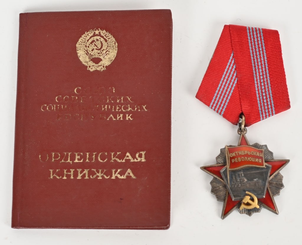 SOVIET ORDER OF THE OCTOBER REVOLUTION W BOOKLET: Instituted in 1967. Three-piece construction, in silver with red enamels, the hammer and sickle insignia in silver gilt, mint marked (Monetny Dvor) and number engraved "61945" on the reverse, measurin