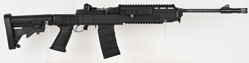 RUGER MINI-14 RIFLE WITH TAPCO T6 FUSION STOCK: SERIAL NUMBER: 185-77688. BARREL: 16". CALIBER: .223. MANUFACTURED: 1989. Ranch rifle configuration barrel with ported flash hider. Standard blade front sight and peep rear aperture. Original blued fi