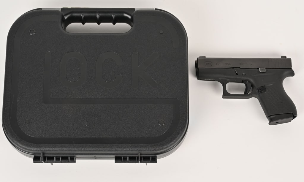 GLOCK MODEL 42 SEMI AUTO PISTOL WITH CASE: SERIAL NUMBER: AAPK510. BARREL: 3". CALIBER: .380 ACP. MANUFACTURED: 2013. Made in the U.S. Factory Trijicon H3 sights,blued slide and black polymer frame. Includes two factory 6 round magazines, manu