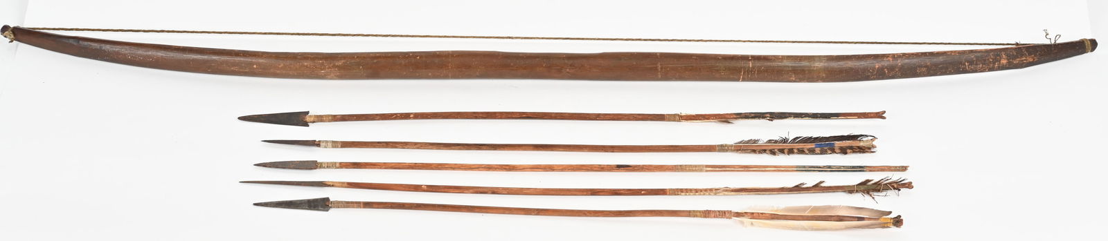 NATIVE AMERICAN BOW AND 5 IRON TIPPED ARROWS: Bow 45" overall, twisted sinew bow string is frayed, 5 arrows are similar make, about 26" each overall, sinew tied feathers & iron points. CONDITION: good overall, bow very good overall with hand worn