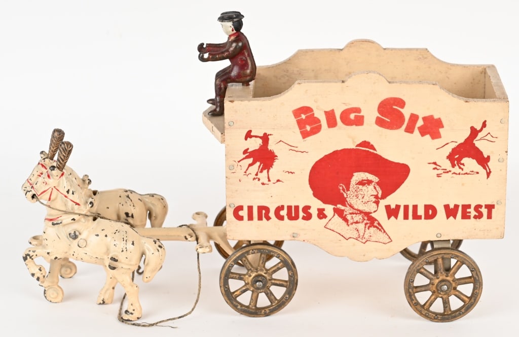 ARCADE BIG SIX CIRCUS WILD WEST WAGON: Arcade cast iron and wood Big Six Circus Wild west horse drawn wagon. Nice original condition. Includes cast iron driver, original horse plumes, and replacement elephant for display. A very nice examp