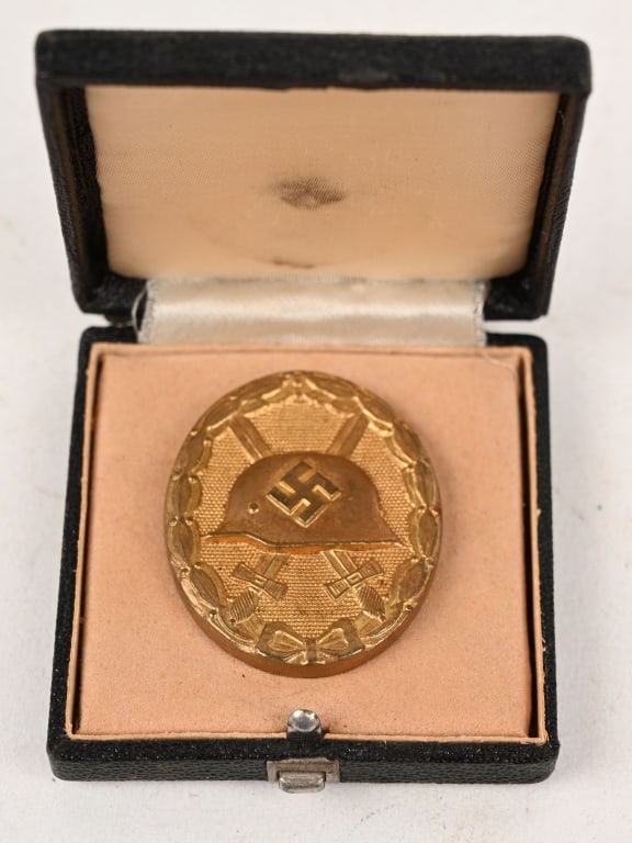 WWII NAZI GERMAN CASED GOLD WOUND BADGE WW2: 1939 pattern, die struck, alloy construction, solid backed badge with a gilt wash. The badge is in the form of an embossed, vertically oval, laurel leaf wreath encompassing an embossed profile of a M3
