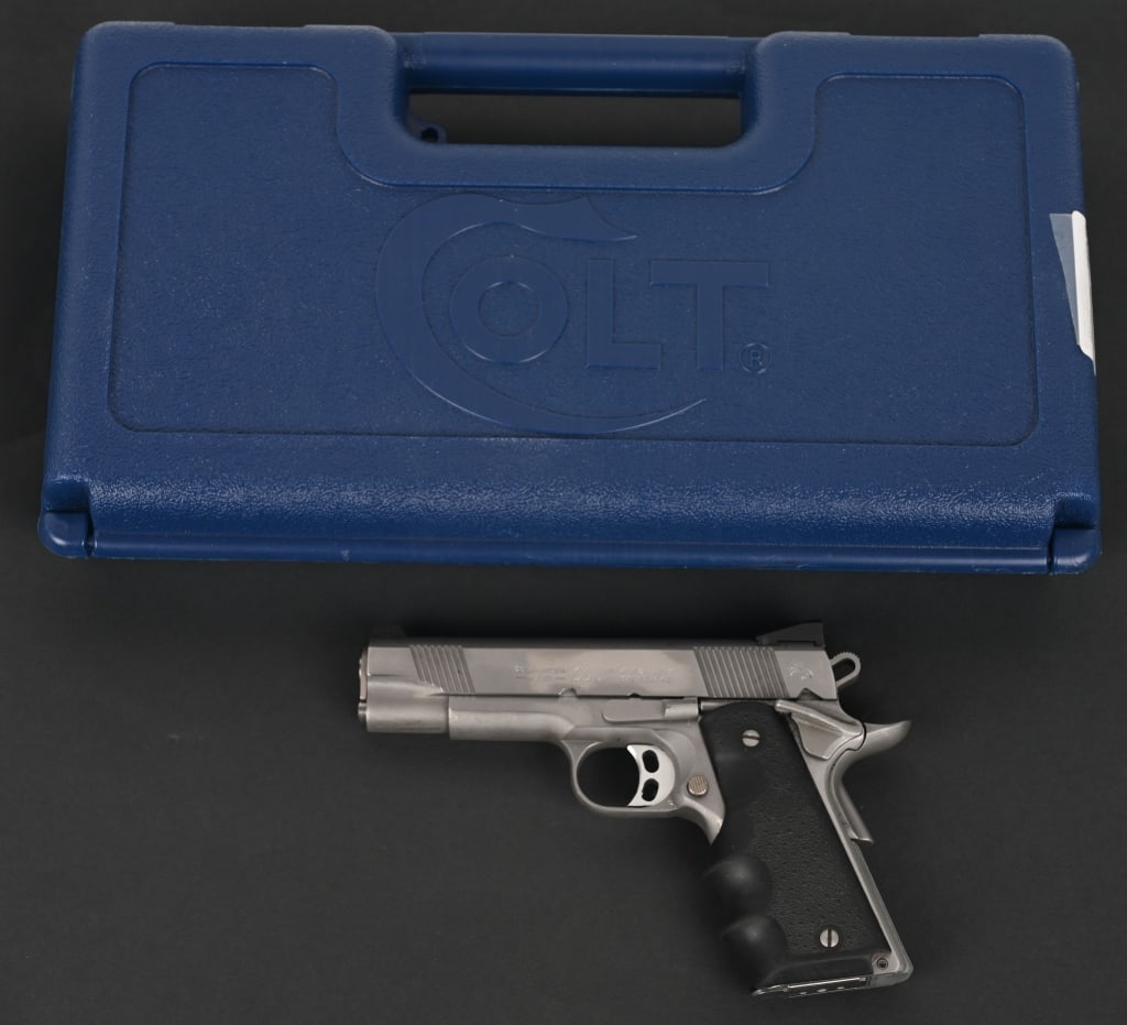 COLT STAINLESS STEEL COMBAT COMMANDER MODEL PISTOL: SERIAL NUMBER: FC21800E. BARREL: ". CALIBER: .45 ACP. This pistol is an all stainless short barrel version of the 1911 with full size grip frame. It features beveled ejection port, light weight hammer