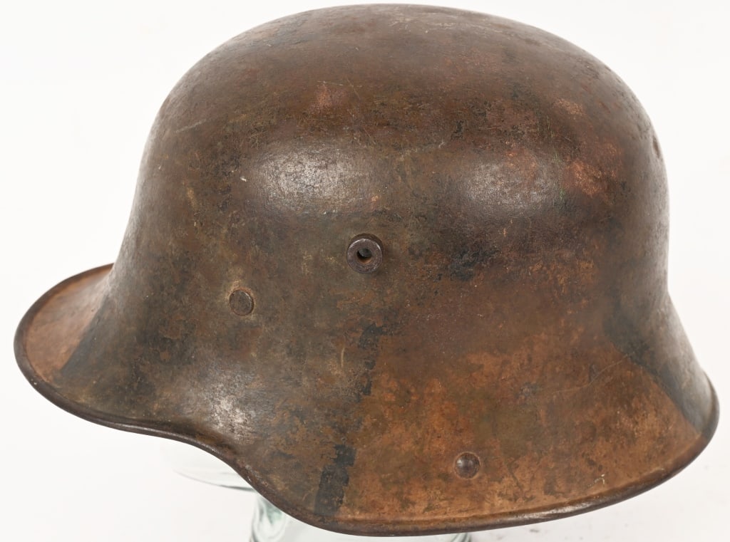 WW1 IMPERIAL GERMAN M17 CAMOUFLAGE HELMET W LINER: The stamped, sheet steel construction helmet retains a good portion of its hand painted, camouflage paint. The camouflage paint is in shades of dark green and yellow in a random patch pattern with the