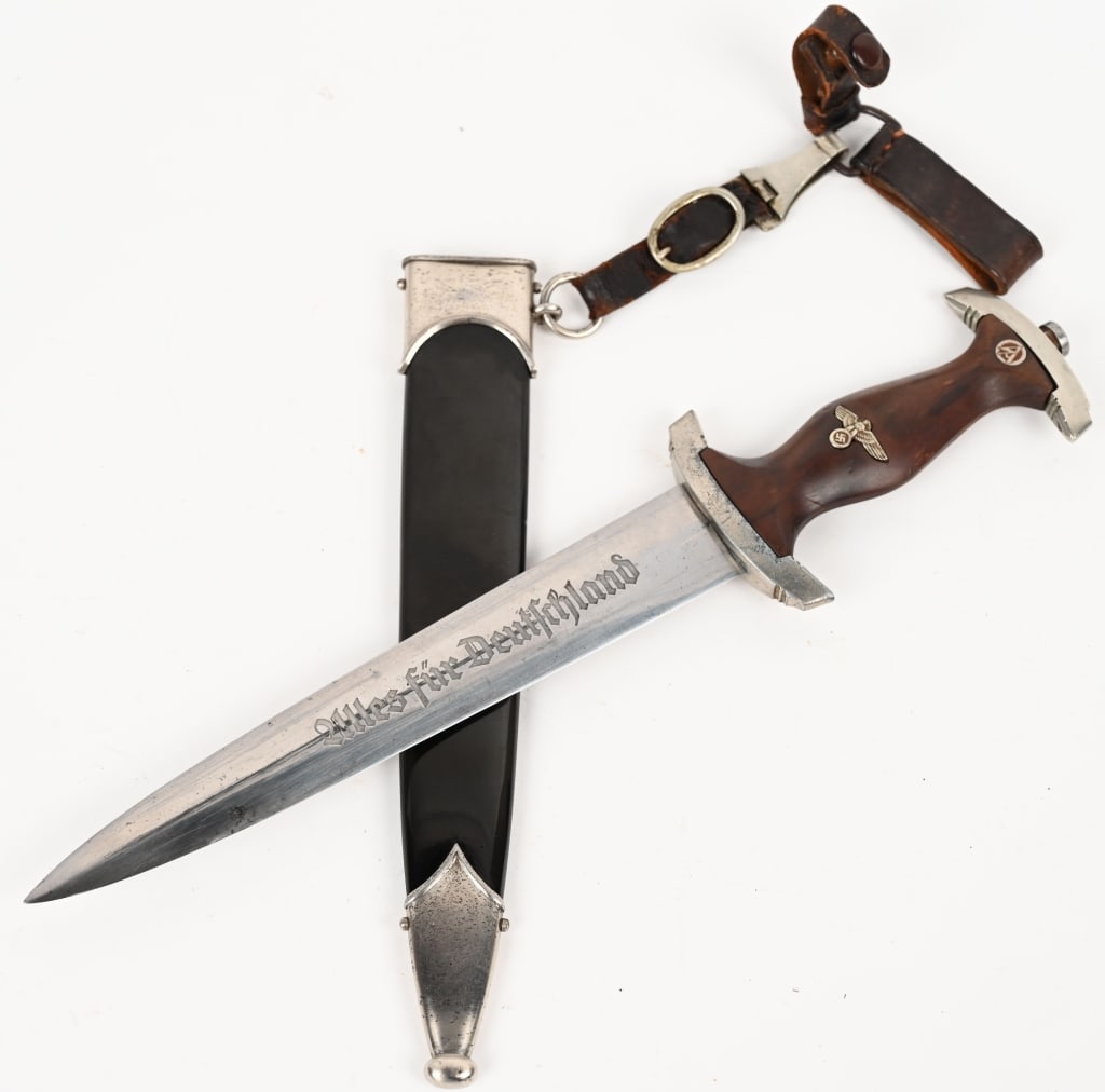 WWII NAZI GERMAN NSKK DAGGER BY J.P. SAUER & SOHN: Double edged, nickel/silver plated blade with a low central ridge. Blade is in overall excellent condition with original cross-graining still visible. Shows the normal scabbard runner marks and typica