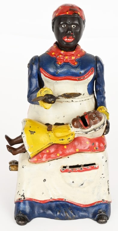 KYSER & REX MAMMY & CHILD MECHANICAL BANK: Mammy and Child cast iron mechanical bank. Desirable blue dress version. The bank has very strong paint. It is all original except for the front part of the spoon which appears replaced.. There are no