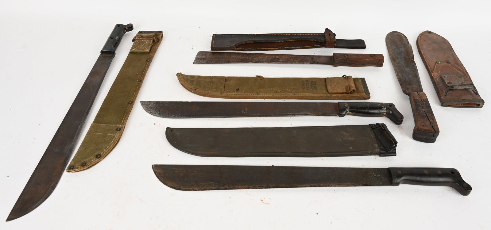 A HIGH CHARACTER LOT OF MACHETES: (1) Collins & Co. machete with canvas scabbard. Blade: 17 3/4". OAL: 23 1/4". The blade is marked " us, legitimus, commins & co 1945". Scabbard is marked "US ATLAS 1943. Condition: Fair. Handle is loo