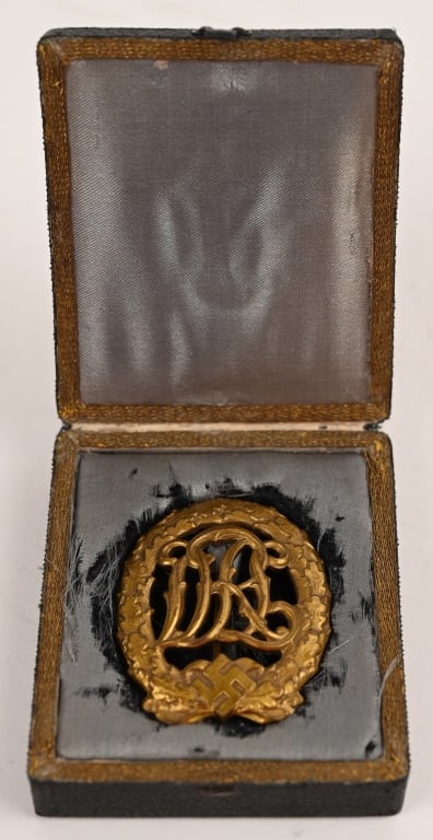 WWII NAZI GERMAN CASED DRL SPORTS BADGE IN BRONZE: A 1937 pattern, die struck bronze award. The badge is in the form of a 1 7/8" tall, vertical oval oak leaf wreath, with a mobile swastika and bow to its base, encompassing the stylized, cut-out letter