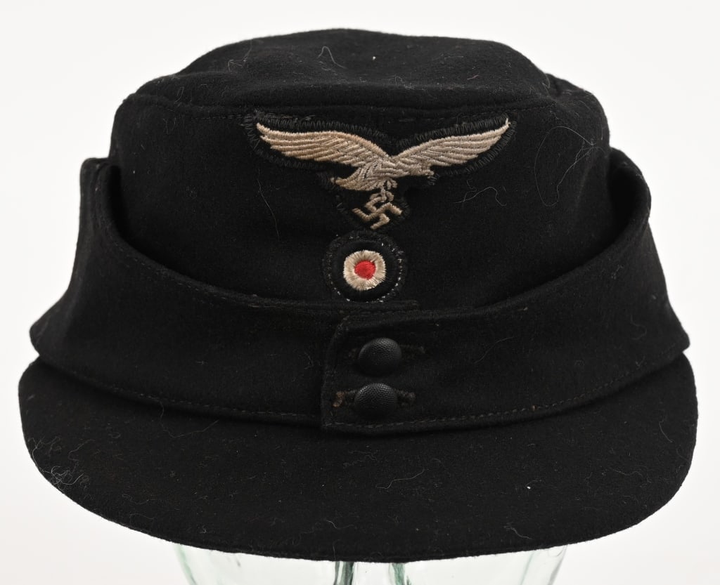 WWII NAZI LUFTWAFFE HERMANN GORING DIVISION CAP: WWII Nazi German Luftwaffe Hermann Goring Panzer Division M43 hat constructed of heavy black wool. The embroidered Luftwaffe eagle and kokarde is machine stitched. The two fold down side panels are se