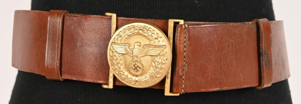 WWII NAZI NSDAP POLITICAL LEADER'S BELT & BUCKLE: A 57mm wide, 105cm long, Havana brown leather belt, with its cast, gilt-washed aluminum belt buckle. The roughly 56mm diameter buckle features, to its convex obverse, a spread-winged eagle clutching a