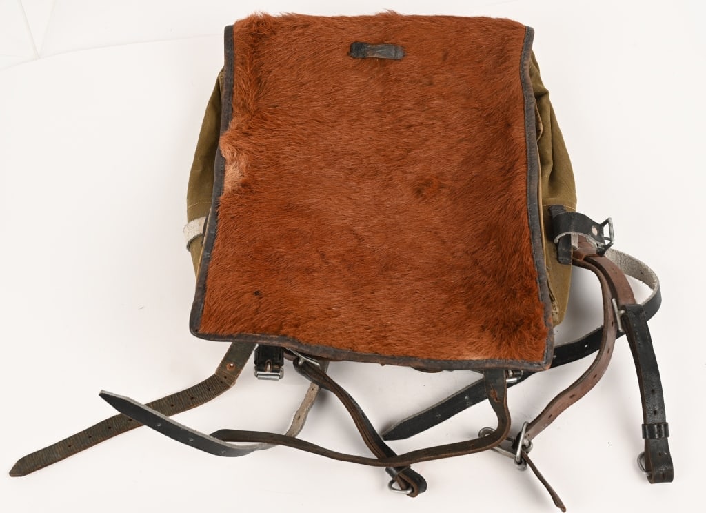 WWII NAZI GERMAN M34 PONY FUR BACKPACK COMPLETE: An olive drab canvas pack with leather and cowhide fittings, roughly 31cm wide, 39cm tall and 6cm deep, with a fold-over flap that covers its entire front. Decent fur coverage to the main flap. All th