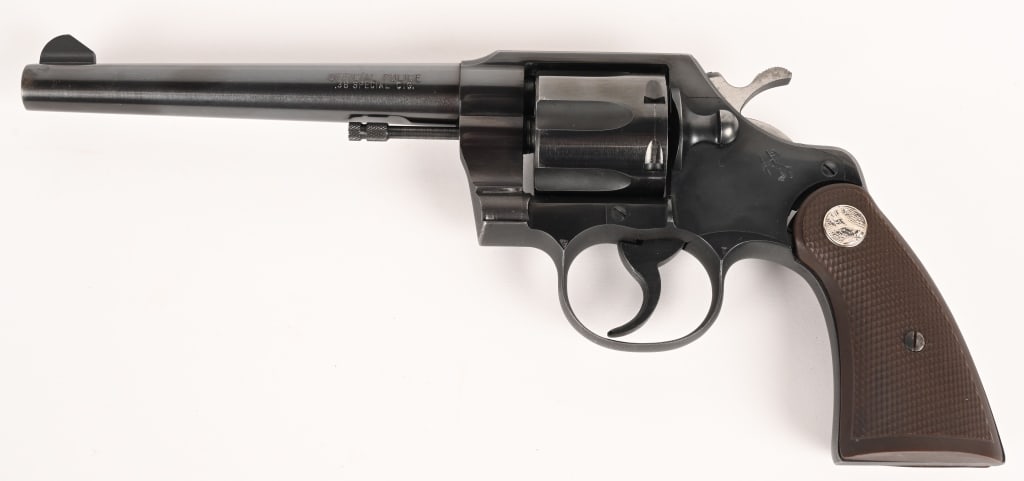 COLT OFFICIAL POLICE HEAVY BARREL REVOLVER 38 SPL: SERIAL NUMBER: 833987 BARREL: 6" CALIBER: 38 SPL. MANUFACTURED: 1954. Metal is blue steel with polished hammer and standard sights. Wood Colt logo checkered grips. CONDITION: metal is 99% with bright