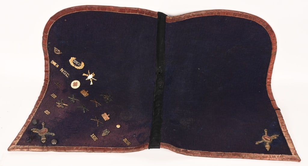SPAN AM OFFICER'S SADDLE CLOTH SHABRAQUE W BADGES: Spanish American War Era midnight blue wool cloth shabraque, or saddle cloth, trimmed with red leather edging with large Coastal Artillery Gilded Brass insignia to each side with enamel. Attached to o