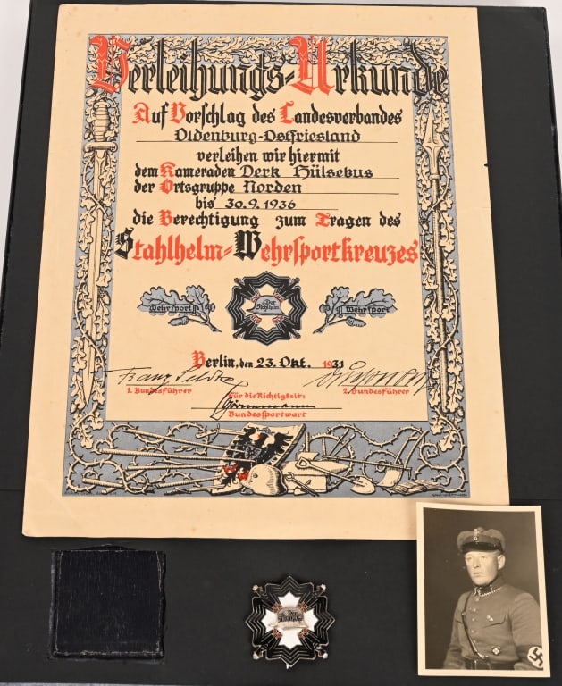 DER STAHLHELM WEHRSPRORTKREUZ AWARD W DOCUMENT: (Der Stahlhelm Wehrsportkreuz mit Etui, Verleihungsurkunde, und Foto). A rare and exceptional Der Stahlhelm Wehrsportkreuz set, including: 1. A Wehrsportkreuz, constructed of silvered bronze with mult