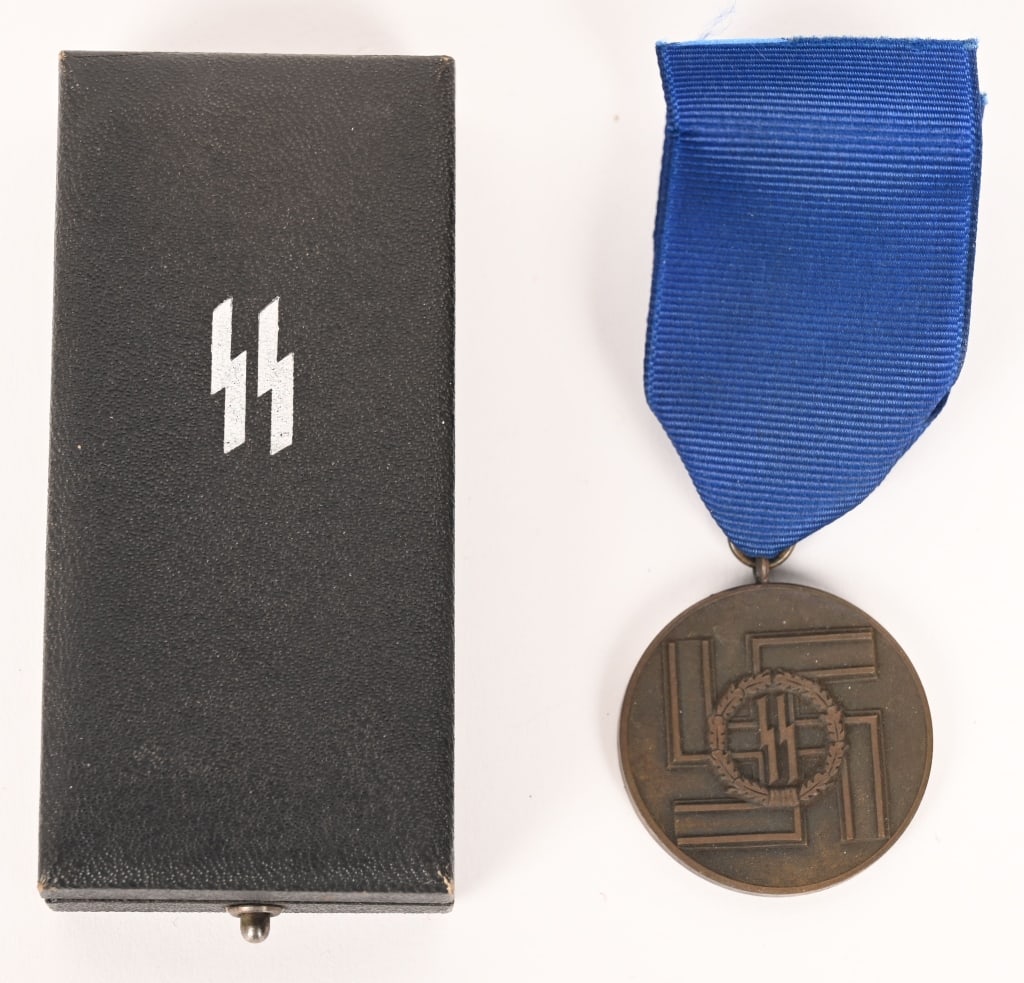 WWII NAZI GERMAN SS EIGHT YEAR LONG SERVICE MEDAL: Roughly 38mm, diameter, die struck bronze alloy construction, third class award with a bronze wash, features a raised outer lip with central, embossed, SS runes encircled by an embossed oak-leaf wreat