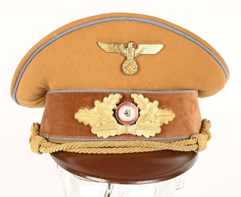 WWII ORTS LEVEL NSDAP POLITICAL LEADER'S VISOR CAP: A 1939 pattern tan-colored, fine whipcord-weave, wool/rayon construction visor cap. The cap features a one-piece circular crown, piped in blue, a body with seams to each of its cardinal points, a one-