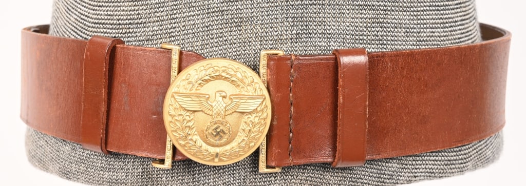 WWII NAZI NSDAP POLITICAL LEADER'S BELT & BUCKLE: A 57mm wide, 95cm long, Havana brown leather belt, with its cast, gilt-washed aluminum belt buckle. The roughly 56mm diameter buckle features, to its convex obverse, a spread-winged eagle clutching a