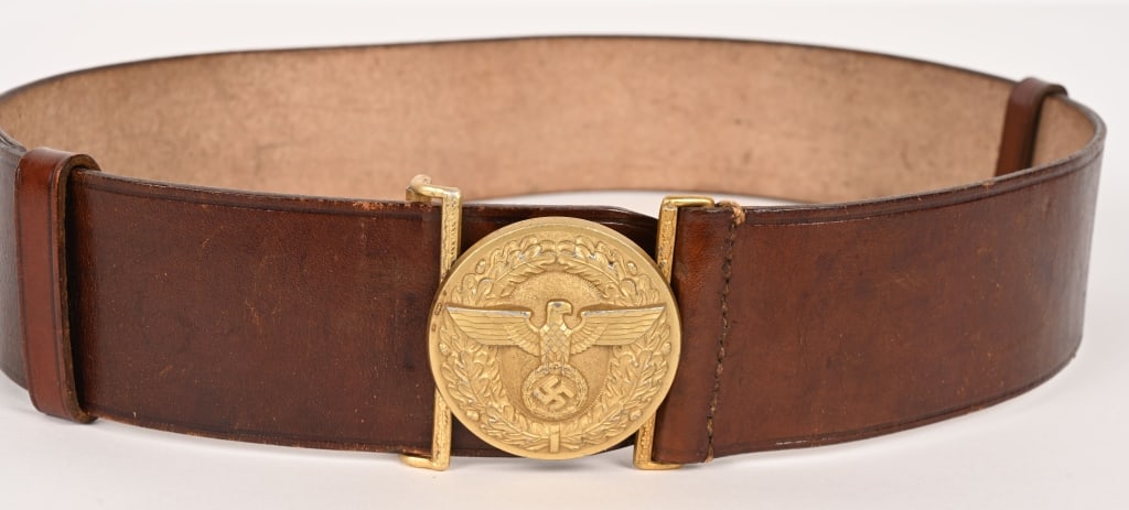 WWII NAZI NSDAP POLITICAL LEADER'S BELT & BUCKLE: A 57mm wide, 95cm long, Havana brown leather belt, with its cast, gilt-washed aluminum belt buckle. The roughly 56mm diameter buckle features, to its convex obverse, a spread-winged eagle clutching a