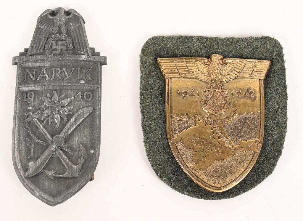WWII NAZI GERMAN CAMPAIGN SHIELD LOT KRIM NARVIK: Lot of two, Campaign Shield Badges to include 1) HEER KRIM CAMPAIGN SHIELD. The award is in the form of a vertical, die stamped, sheet metal construction, shield with a bronze wash featuring a large e