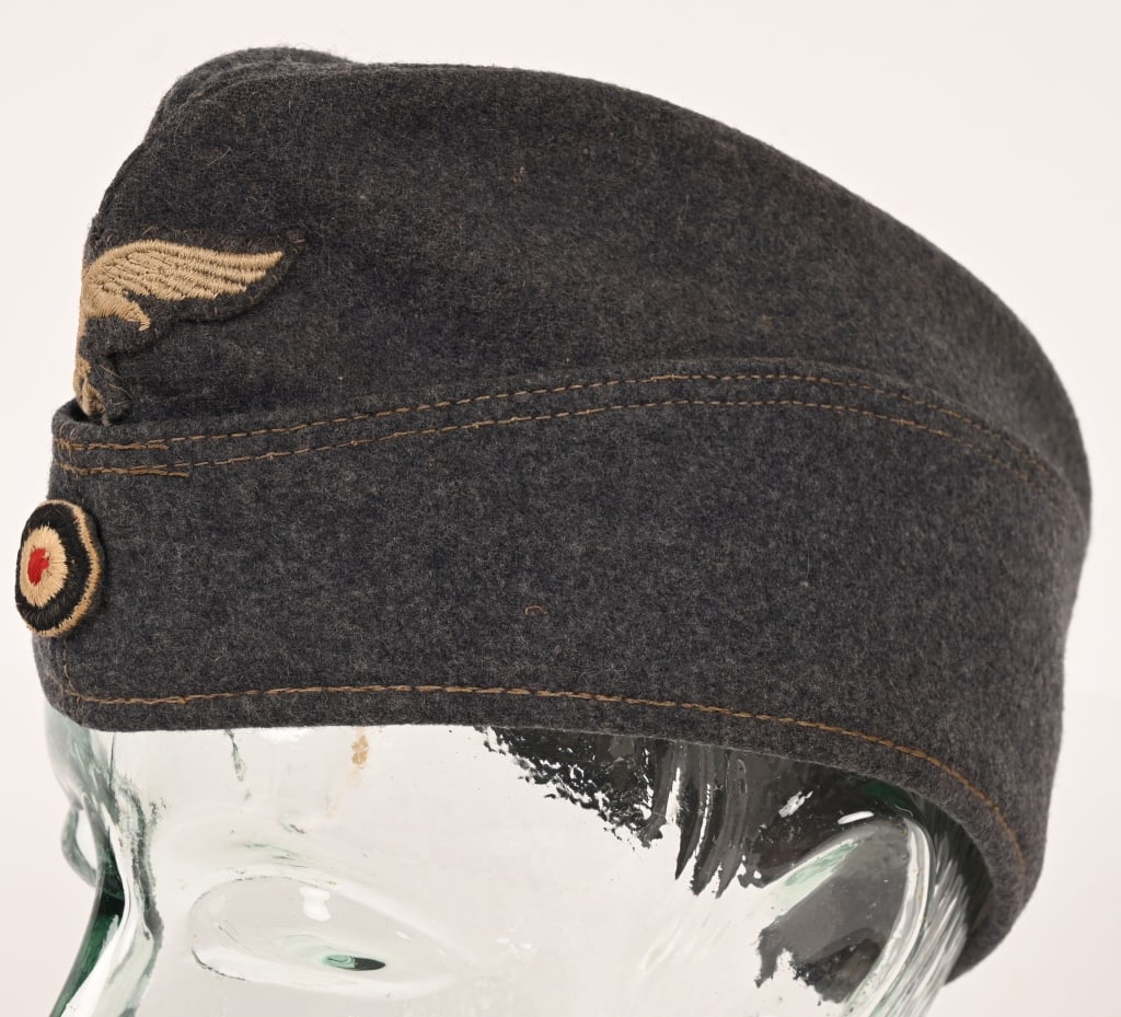 WWII NAZI GERMAN LUFTWAFFE EM/NCO'S OVERSEAS CAP: Luftwaffe blue/gray wool/rayon blend construction cap features fold down side and back panels with gently sloping downward scallops to the front and forward sides. The front center of the cap has a ma