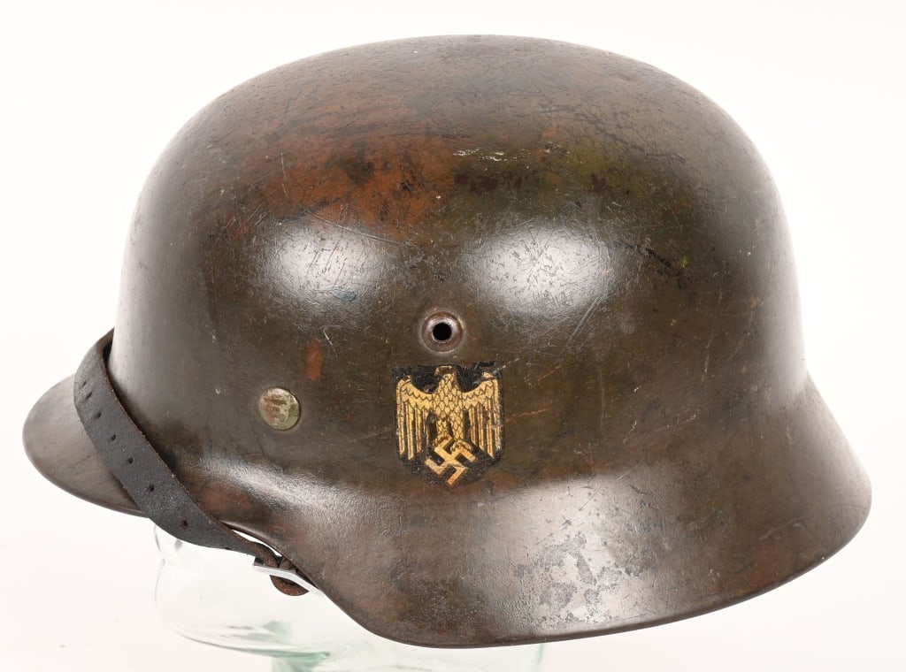 WWII NAZI GERMAN NORMANDY CAMO M35 HELMET WW2: The stamped, sheet steel construction helmet retains a good portion of its field-applied, camouflage over-paint in random splotches of green and tan. All three liner retaining rivets are intact. The l