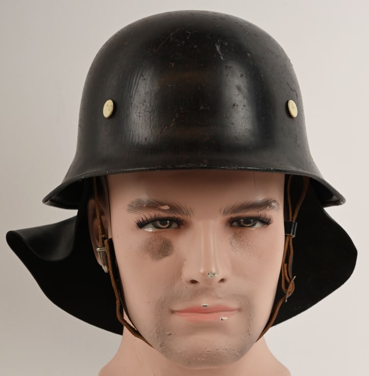 WWII NAZI M34 FEUERSCHUTZPOLIZEI HELMET W LINER: The stamped, sheet steel construction helmet retains a good portion of its original black paint. The helmet has two separate, groups of seven, "salt & pepper" ventilation holes positioned on each side