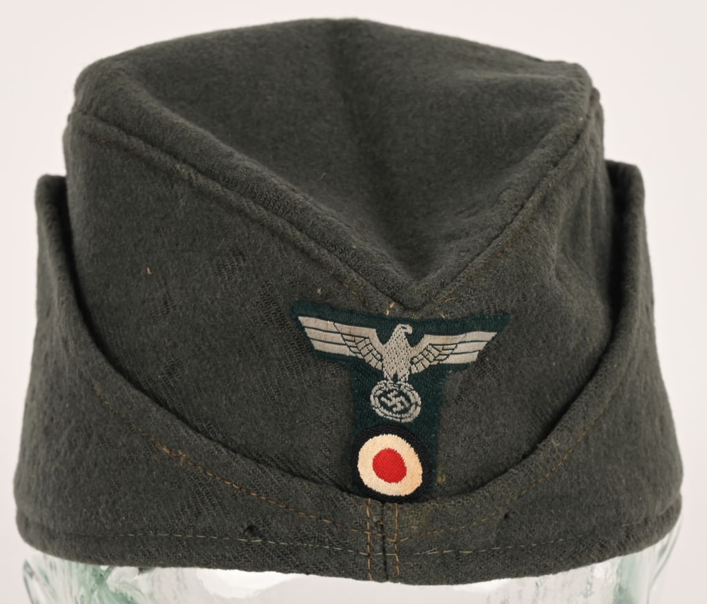 WWII NAZI GERMAN EM/NCO'S MOUNTAIN OVERSEAS CAP: Field-gray wool/rayon blend construction cap T-Shaped insignia is original stitching to the cap. Interior of cap is fully lined in light weight, brown/green cotton/rayon. Maker marked to Karl Naubert.