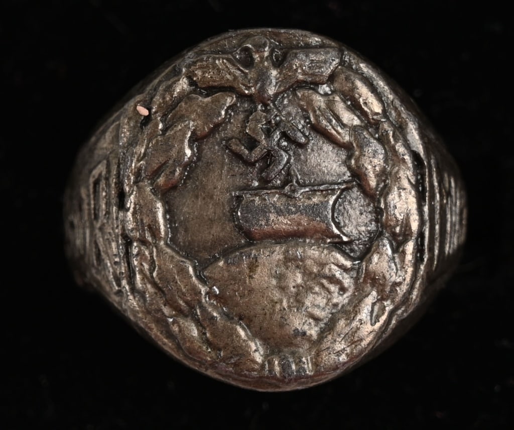 WWII NAZI KRIEGSMARINE AUXILIARY CRUISER RING WW2: WWII Kriegsmarine Auxiliary Cruiser Mens Ring. To the front of the ring having a Auxiliary Cruiser Badge in design, flanked by text that is difficult to read due to being worn. Excellent. Th