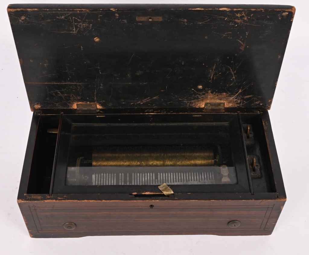 BRASS CYLINDER MUSIC BOX: Brass cylinder music box, likely of Swiss origin. The machine worked when tested. It is missing 4 teeth on the comb and the case has wear and some damage to the lid. The lock is missing. Good for