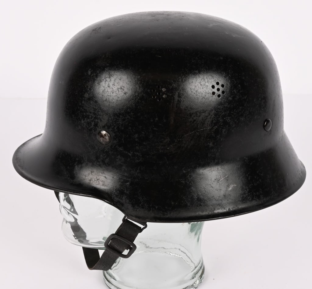 NAZI M34 FEUERSCHUTZPOLIZEI HELMET WITH LINER WW2: The stamped, sheet steel construction, civic M34 helmet retains most of its black paint . The helmet has two separate, groups of seven, "salt & pepper" ventilation holes positioned on each side of the
