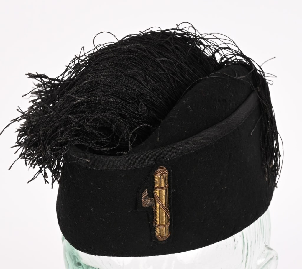 WWII ITALIAN BLACK SHIRT MVSN FASCIST FEZ WW2: A black wool constructed cap that features all around side panels with vertically ribbed black rayon trim to the top edges which encompass the central oval crown. To the top of the Fez is a multi-stra