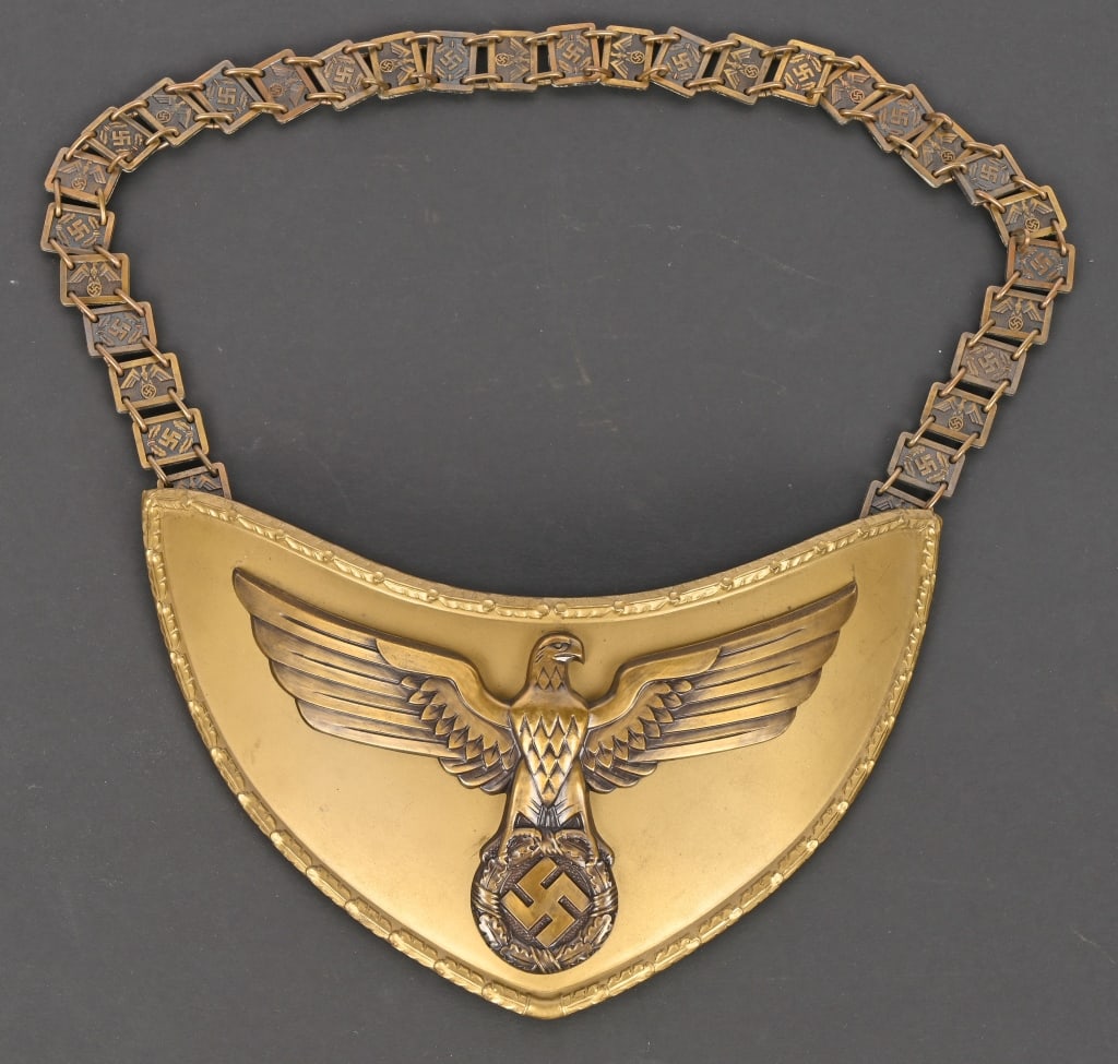 WWII NSDAP POLITICAL LEADER FLAG BEARER'S GORGET: Stamped alloy gorget with a bronze wash. The half-moon shaped gorget measures roughly, 24cm wide from upper tip to tip and 12cm tall. The gorget features a separate, stylized, bronze washed, embossed 