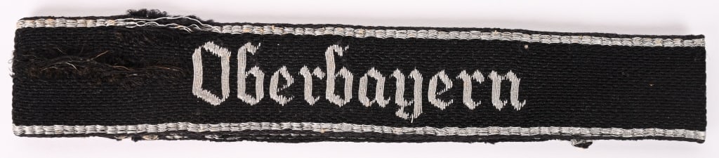 WWII NAZI SS TV OBERBAYERN STANDARTE CUFFTITLE: An Officer's SSTV "Oberbayern" Cufftitle 1st Version; black rayon construction, machine woven, with machine embroidered "Oberbayern" in silvery/grey metallic flat wires; the cufftitle is bordered at b