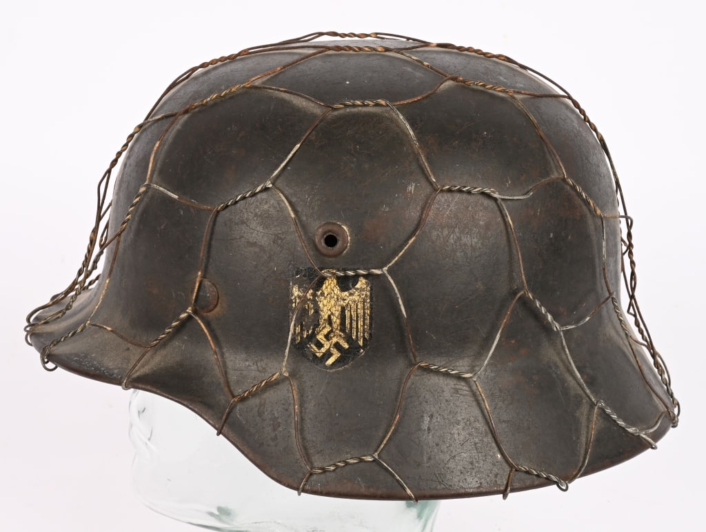 WWII NAZI GERMAN HEER CHICKEN WIRE CAMO HELMET WW2: The stamped, sheet steel construction helmet has a light even patina of surface rust and dirt. The left side of the helmet has an Wehrmacht eagle shield decal featuring a eagle with down-swept wings, 