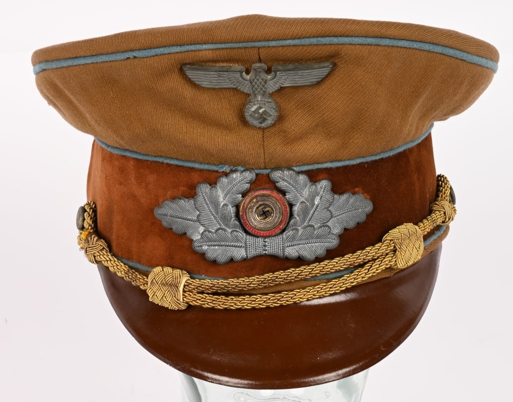 WWII GERMAN NSDAP ORTSGRUPPE LEADER VISOR CAP: A 1939 pattern tan-colored, fine whipcord-weave, wool/rayon construction visor cap. The cap features a one-piece circular crown, piped in blue, a body with seams to each of its cardinal points, a one-