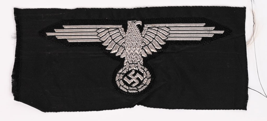 WWII NAZI GERMAN WAFFEN SS BEVO SLEEVE EAGLE WW2: Second pattern, (Circa 1939-1945), machine woven SS sleeve eagle with out-stretched wings, clutching a wreathed, canted, swastika in it’s talons in silvery/grey rayon threads on a woven, black, 
