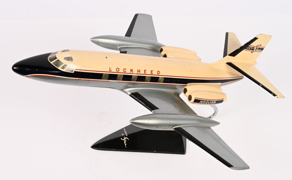 LOCKHEED JETSTAR METAL DESK MODEL WITH STAND: Lockheed JetStar metal desktop airplane model with arm and base measuring 13 1/2 wingspan. The metal appears to be aluminum as it is non-ferrous (magnet does not adhere). The aircraft model can be rem