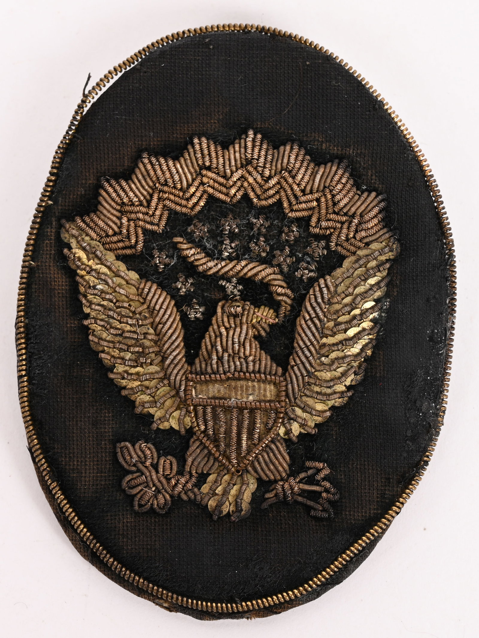 CIVIL WAR OFFICERS BULLION HARDEE HAT BADGE: U.S. Army officer’s embroidered insignia for the Hardee or slouch hat. Used to pin up the brim on one side. Spread-winged eagle of bullion thread and sequins on black velvet. Brown cloth backing. On