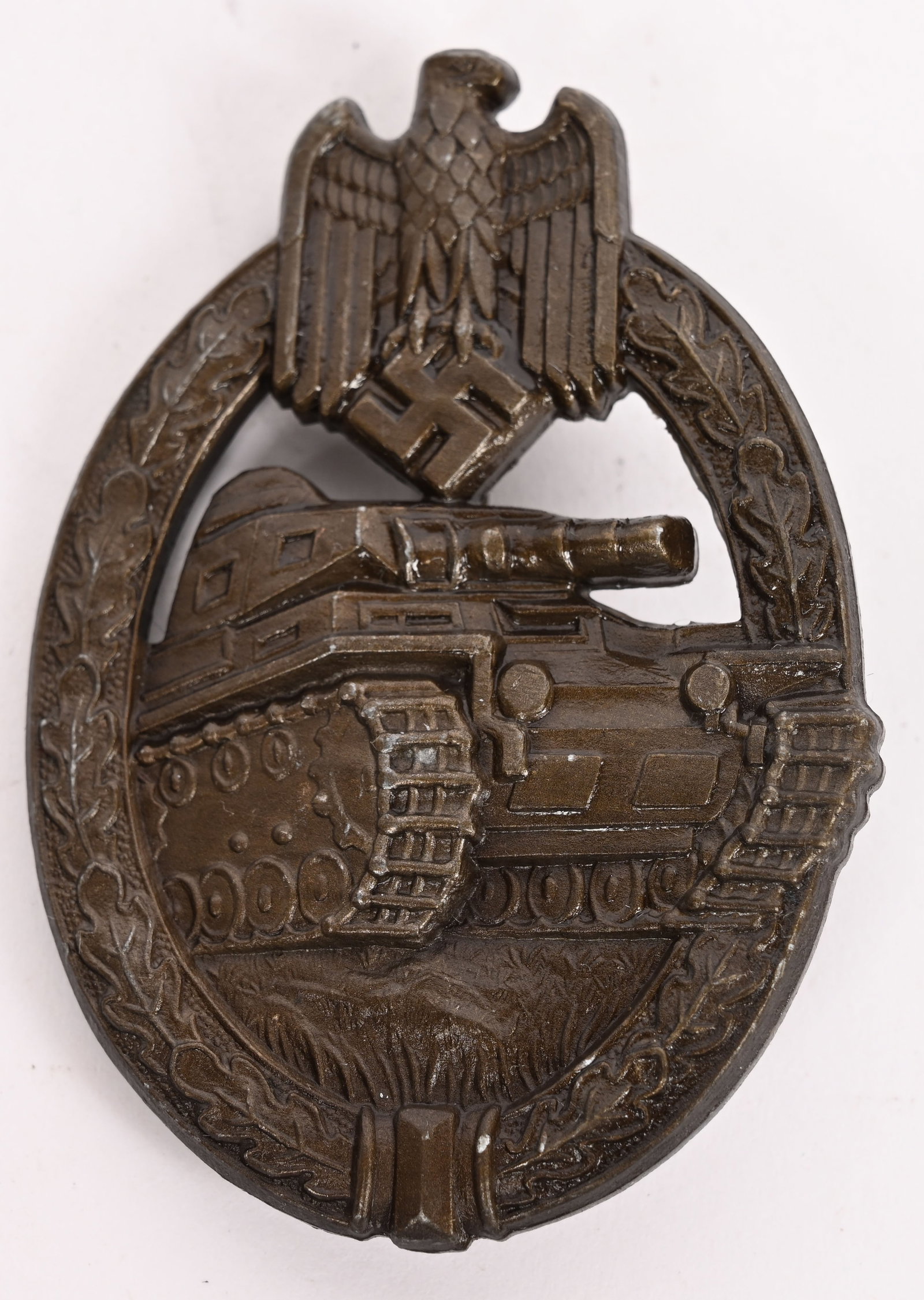 WWII NAZI PANZER ASSAULT BADGE IN BRONZE H. AURICH: German World War II Army Bronze Tank Assault Badge. The front shows a tank in the center with a German eagle clutching a swastika in his talons at the top. Both are surrounded by an oval oak leaf wrea