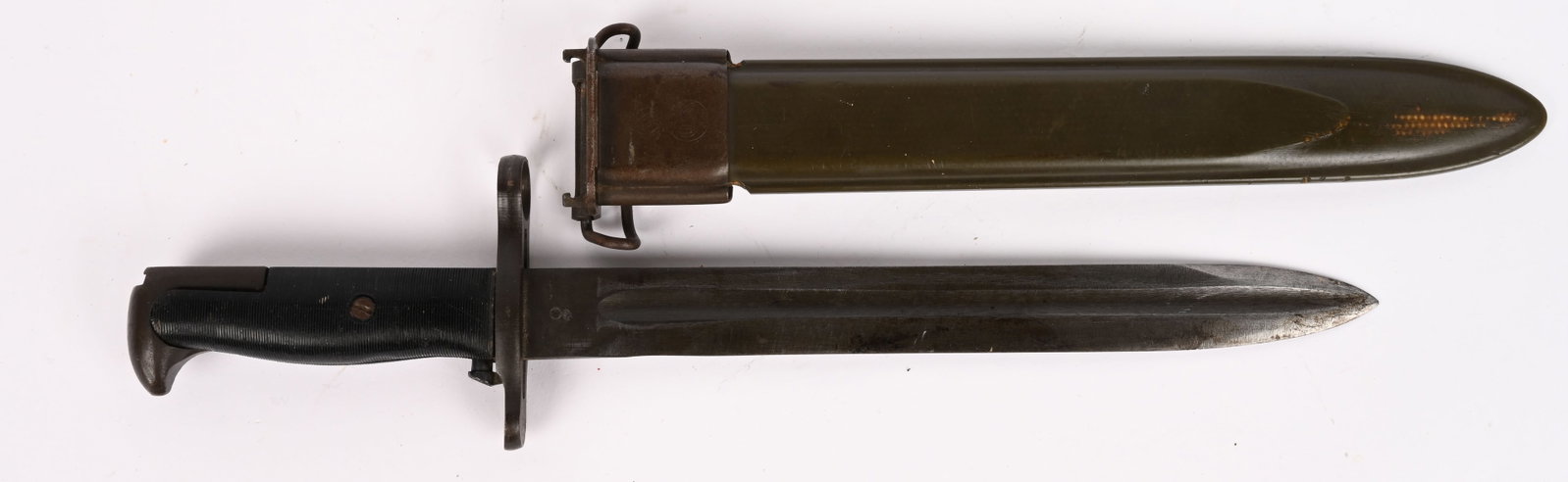WWII US ARMY M1 GARAND BAYONET UFH WW2: A parkerized bayonet with black bakelite grips and an olive drab metal and composite material scabbard. Its 25cm, single-edged blade, with a swedge and long fullers, retains most of its original bluin