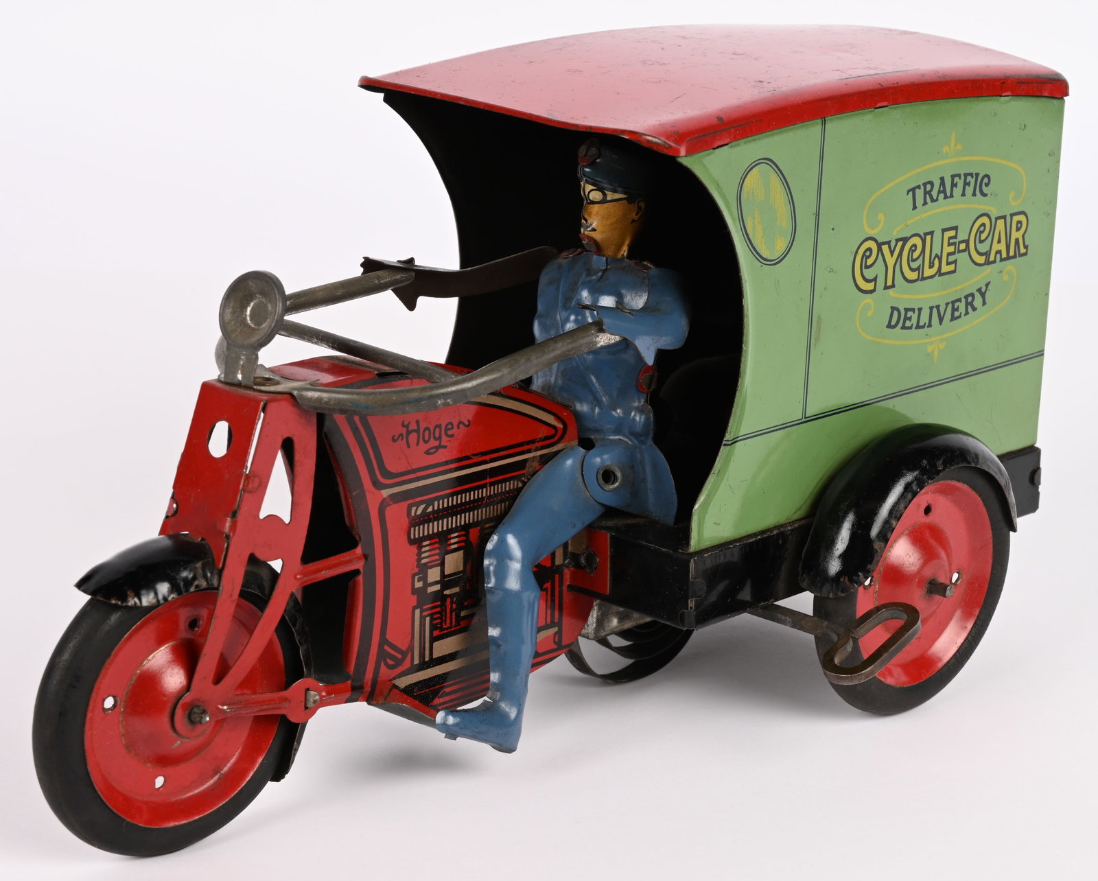 HOGE WINDUP TRAFFIC DELIVERY CYCLE-CAR: Hoge windup Traffic Delivery Cycle-Car motorcycle. Complete and original. Nice graphics features 4 cylinder motor with delivery back end. Full figured tin driver. This is the early version with rear