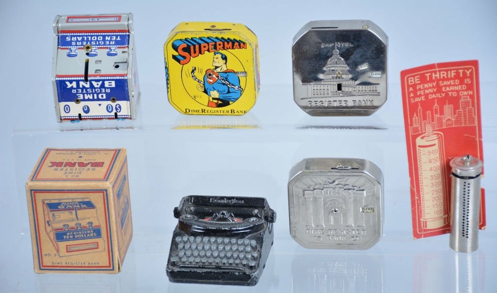 Lot of 6 Vintage Dime Banks: Remington typewriter die cast bank, Superman bank, and 2 Lucky banks, cylinder bank on original card, register bank in box all very good to excellent.