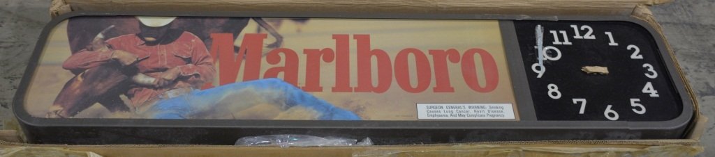 MARLBORO CIGARETTES ADVERTISING CLOCK: Excellent Marlboro Cigarettes Advertising Clock unused in original shipping box. This is a light up sign with clock. Great image or Marlboro Man wrestling Bull. Large sign measures 54"x13". dated 1995
