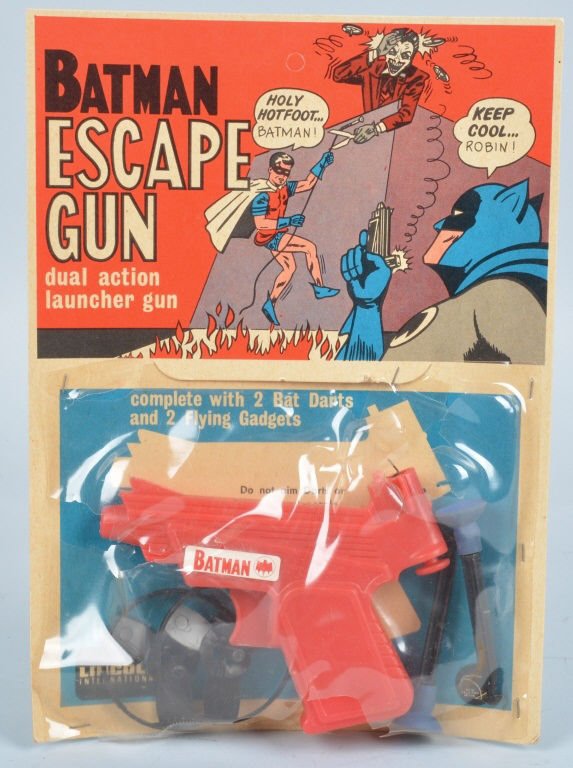 BATMAN ESCAPE GUN ON ORIGINAL CARD, VINTAGE: Great looking toy gun with 2 bat darts, and 2 flying gadgets. Still on original colorful unpucnhed card. Some damage to plastic on package. Excellent