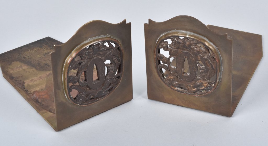 JAPANESE TSUBA BOOKENDS, POTTER STUDIOS: Measure 7" long 5" high, tsuba diameter is 3 1/4". Nice pair of brass bookends with Tsubas inset on the ends. Marked Potter Studios E103. Very Good